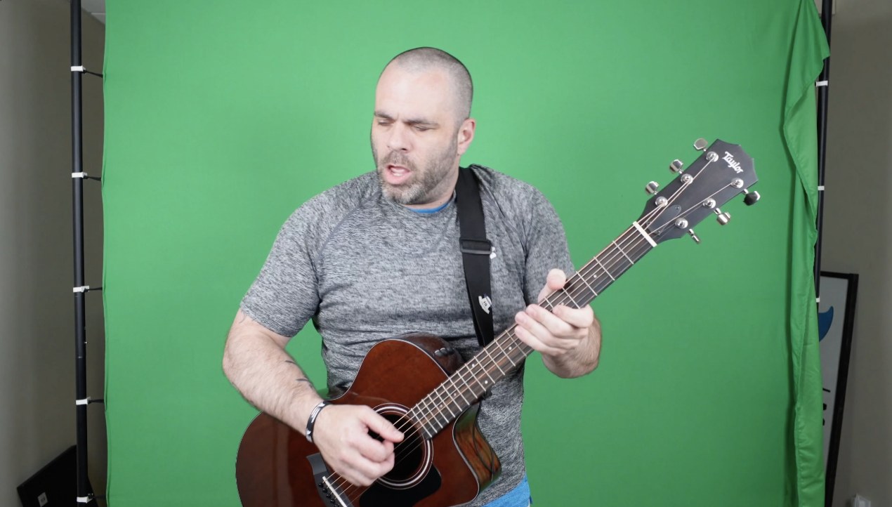 CJ Tuttle on green screen with his Taylor guitar